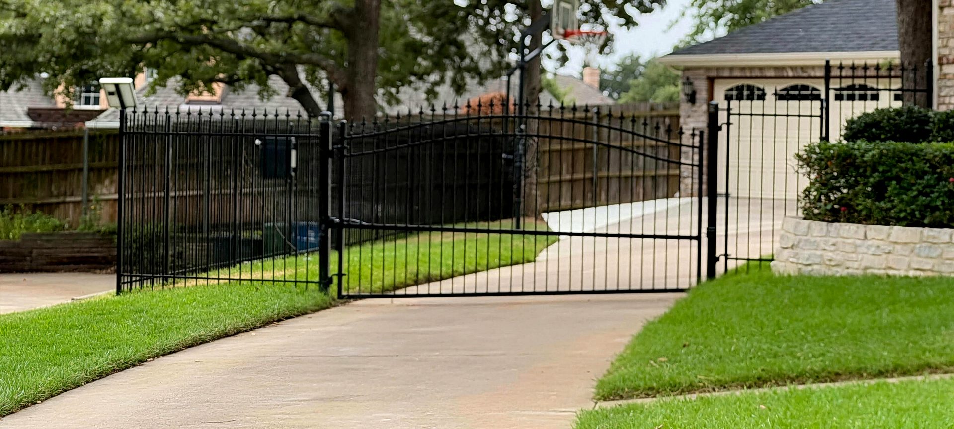 Arched wrought iron double drive gate across a residential driveway